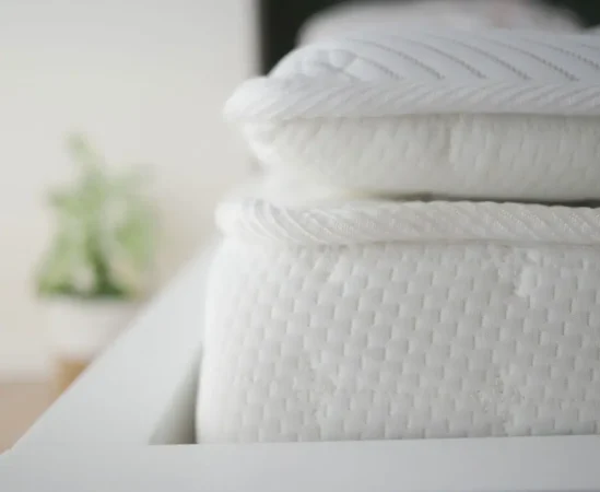 Close-up of stacked white mattresses on bed frame.